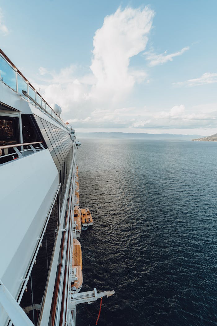 A cruise ship sails through the calm blue ocean on a clear day.