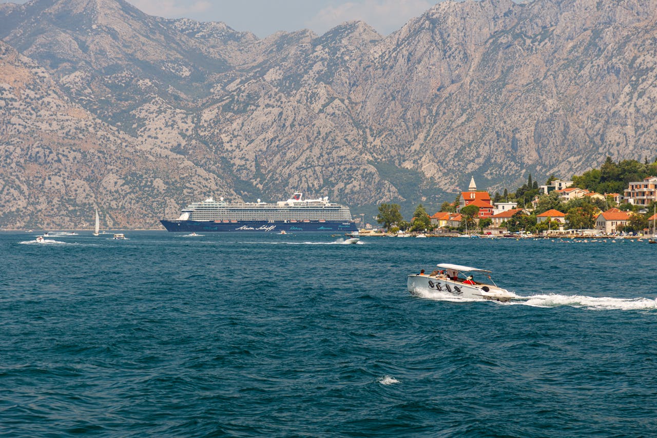 Cruise ship and speedboat in scenic Montenegro bay with mountain backdrop, offering a perfect travel moment.