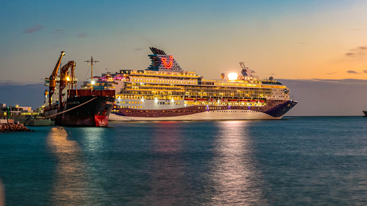 A luxurious cruise ship docked at Málaga harbor during a vibrant sunset.